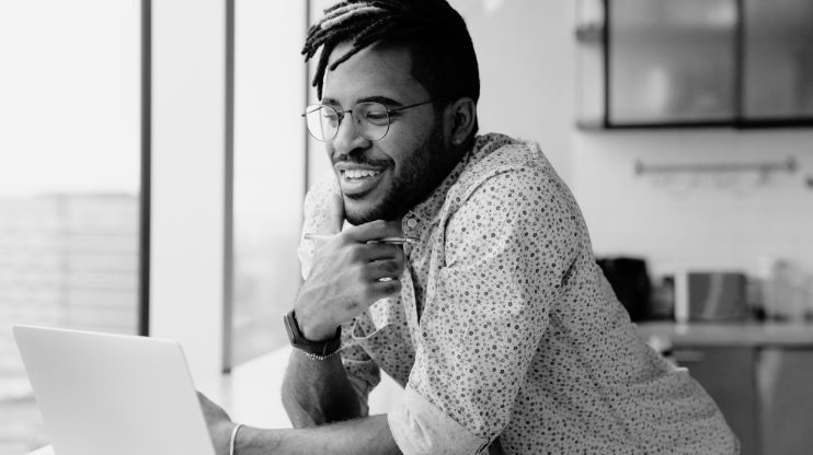 A man smiling looking at a laptop