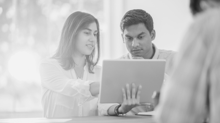 Two people chatting and looking at a laptop